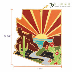 The Arizona Cutting Board by Totally Bamboo, featuring artwork by Summer Stokes, is a beautifully crafted piece shaped like the state of Arizona. It highlights a vibrant desert scene with a cactus, river, and mountains beneath a sunburst sky. Measuring 13-1/2 inches in height and 11-3/4 inches in width, the "Totally Bamboo" logo suggests quality craftsmanship reminiscent of Summer Stokes' art.