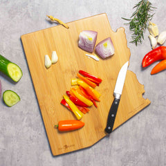 Vegetables are beautifully displayed on an Arizona Cutting Board, featuring artwork by Summer Stokes and crafted by Totally Bamboo, accompanied by a knife and more vibrant veggies, ready to be transformed into a delightful dish.