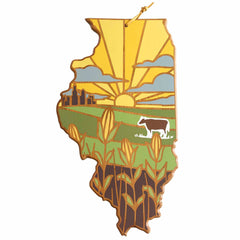 The Illinois Cutting Board with Artwork by Summer Stokes, offered by Totally Bamboo, features a vibrant design of a colorful landscape in the shape of Illinois. It includes a rising sun, farmland, a cow, and cornstalks against a yellow and blue sky backdrop with a city silhouette, beautifully capturing the essence of state-shaped cutting boards.