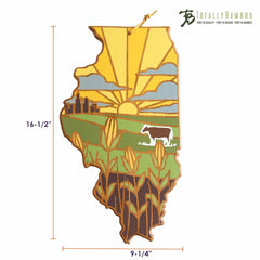 The Illinois Cutting Board with Artwork by Summer Stokes from Totally Bamboo is crafted from bamboo and features stunning artwork depicting a landscape with a sunset, cow, fields, and city skyline. Sunrays extend across the sky in this beautiful piece. Measuring 16-1/2" high by 9-1/4" wide, it proudly displays the "Totally Bamboo" logo in the top right corner.