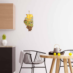 A modern kitchen showcases black chairs and a wooden table adorned with a teapot and lemons. Mounted on a white wall is the Illinois Cutting Board with Artwork by Summer Stokes from Totally Bamboo, featuring a landscape scene. The minimalist decor is completed with stylish touches including Summer Stokes' artwork and a small potted plant.