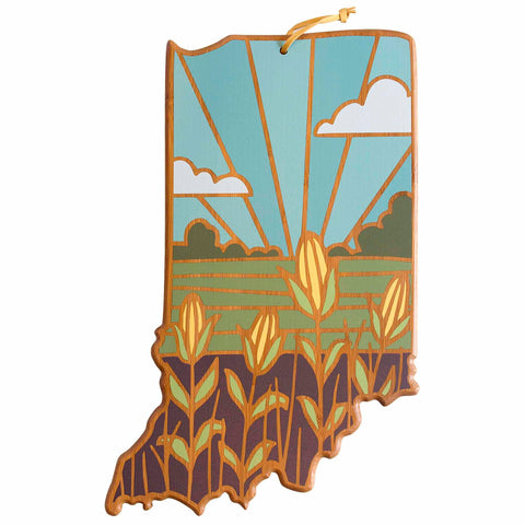 This artwork by Summer Stokes, available as the Indiana Cutting Board from Totally Bamboo, is designed in the shape of the state and offers a bamboo cutting surface decorated with a picturesque landscape. The scene showcases cornfields, clouds, and sun rays rendered in vibrant green, blue, and yellow tones through UV printing.