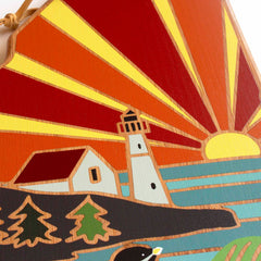 This eye-catching piece by Summer Stokes illustrates a lighthouse and cottage set on a hill beside the water, gleaming in the warm glow of a setting sun with radiant stripes. In the foreground, charming elements like trees and a duck enhance its beauty, similar to how the Maine Cutting Board with Artwork by Summer Stokes from Totally Bamboo adds charm to your kitchen.