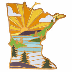 The Minnesota Cutting Board with Artwork by Summer Stokes from Totally Bamboo features a landscape design in the shape of Minnesota, highlighting a sunset, trees, and a river. Dominated by warm hues of yellow, orange, and green, it captures the vibrant charm characteristic of Summer Stokes' natural-inspired artwork.