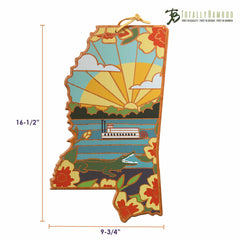 This colorful Mississippi Cutting Board from the Totally Bamboo collection highlights Summer Stokes' artwork, featuring a riverboat set against red and yellow floral designs under a sunset. The dimensions are 16.5 inches tall by 9.75 inches wide, and it's part of the state-shaped cutting boards series.