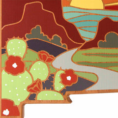 The New Mexico Cutting Board by Totally Bamboo features artwork by Summer Stokes, beautifully capturing a winding river against mountain silhouettes and the sun. In the foreground, vibrant green cacti with red flowers create a striking contrast against earthy tones and bold shapes, reminiscent of state-shaped cutting boards' distinct outlines.