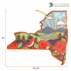 The New York Cutting Board with Artwork by Summer Stokes from Totally Bamboo features vibrant mountains, a sunburst, a bird, and flowers. Measuring 12 inches in height and 13.25 inches in width, it prominently displays "New York" at the top.