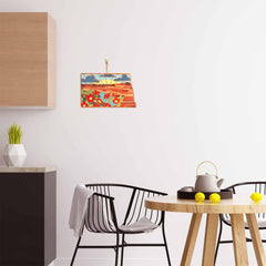 A modern kitchen showcases a round wooden table paired with two black chairs and a teapot. The white wall is adorned with a vibrant artwork by Summer Stokes, depicting mountains and flowers. On the left, a small shelf holds plants that enhance the decor, while state-shaped cutting boards from Totally Bamboo, including the North Dakota Cutting Board featuring Summer Stokes' artwork, are displayed on the counter.