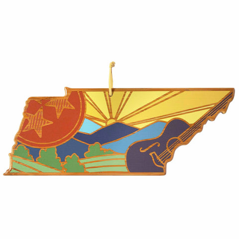 This Tennessee cutting board, featuring artwork by Summer Stokes, is presented by Totally Bamboo. The design captures the essence of Tennessee with vibrant mountains, a setting sun, green hills, and a guitar. Accentuated with stars on a red circle and equipped with a yellow ribbon for hanging, it beautifully echoes the aesthetic of state-shaped ornaments.