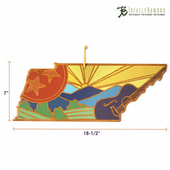 A Tennessee-shaped wooden cutting board, featuring Summer Stokes' vibrant artwork that includes designs of mountains, a guitar, and a sunset. Measuring 7 inches by 18.5 inches, it is elegantly adorned with the Totally Bamboo logo in the top right corner.