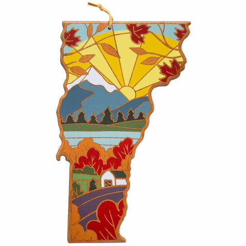 Inspired by Summer Stokes' artwork, this Vermont-shaped stained glass ornament from Totally Bamboo depicts a charming scenic landscape with a radiant sun, mountains, trees, and a cozy house surrounded by autumn leaves. Equipped with an attached string for easy hanging.