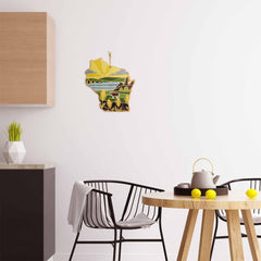 A minimalist kitchen showcases a round wooden table with black chairs. On the table, a white teapot is placed next to some lemons, while the wall is adorned with the vibrant depiction of Wisconsin in yellow and green hues with artwork by Summer Stokes featured on a Totally Bamboo cutting board.