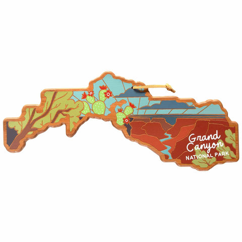 The Grand Canyon Cutting Board with Artwork by Summer Stokes from Totally Bamboo is a wooden decoration featuring vibrant illustrations of the canyon's scenery, complete with cacti and mountains. Utilizing UV printing, it beautifully reads "Grand Canyon National Park," making it a stunning piece for any kitchen or display area.