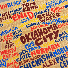 Experience the vibrant style of Wander on Words™ with the Oklahoma Cutting Board by Totally Bamboo, showcasing colorful graphic artwork that features the names of cities and towns such as Oklahoma City, Enid, Norman, and Stillwater. This piece boasts bold, overlapping fonts in bright shades of red, blue, and yellow for a playful aesthetic.